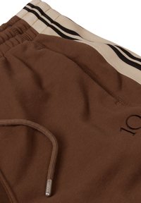 Shorts marron en tissu doux avec une ceinture élastique, ornés de bandes latérales noires et crème et d'un embout de cordon métallique.