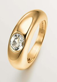 Anillo de oro con un diseño suave y redondeado que presenta una gran piedra preciosa ovalada clara engastada en un acento de bisel pulido.