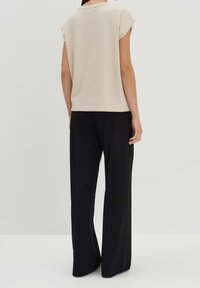 Beige texturerad stickad topp med korta ärmar, i kombination med svarta vida byxor. Minimalistisk design med avslappnad passform.