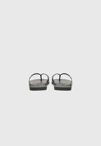 Sorte flip-flops har en flat design med teksturerte gummisåler og tynne stropper. Stropperne er glatte med en metallisk aksent.