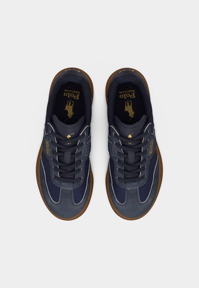 Ζευγάρι ναυτικό μπλε και γκρι αθλητικά παπούτσια Polo Ralph Lauren με καφέ σόλες και μαύρα κορδόνια, που φαίνονται από πάνω σε λευκό φόντο.