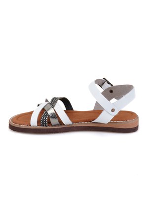 White strappy sandal with silver accents, brown insole, and textured black strap detail. Adjustable ankle strap with buckle closure.