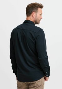 Sötétkék, hosszú ujjú ing, standard gallérral, gombos mandzsettával, hátul pliszével és sima, texturált anyaggal.