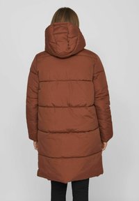 Manteau doudoune marron avec une capuche, comportant des sections matelassées horizontales et une coupe mi-longue. Texture lisse et détails minimaux.