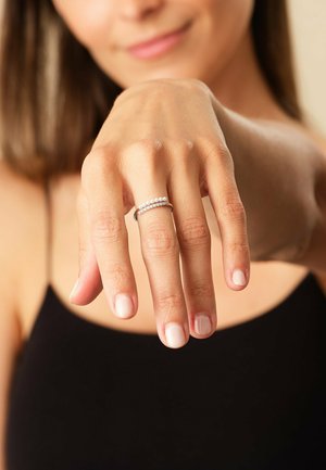 Silberner Ring mit einem glatten Band und einer Reihe kleiner, runder Perlen, präsentiert auf einer Hand mit natürlichen, leicht polierten Nägeln.