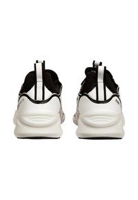 Pantofi sport albi și negri au un exterior neted cu un design cu model, călcâie texturate și o bandă de prindere pentru a facilita îmbrăcarea.