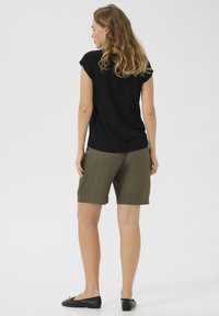Zwart T-shirt met korte mouwen, olijfgroene shorts en zwarte platte schoenen. Fijne stof, relaxed fit en klassiek ontwerp met een simpele silhoeët.