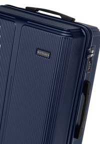 Námořnický tvrdý kufr s texturovaným povrchem, vertikálními drážkami, zámkem a postranní rukojetí. Obsahuje černou logovou destičku s nápisem "WITTCHEN."