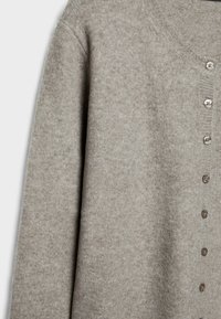 Cardigan grigio chiaro realizzato in morbido tessuto a maglia, con scollatura rotonda e sei bottoni lungo la parte anteriore. Tessuto liscio con dettagli a coste.