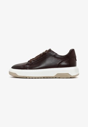 Zapatilla de cuero marrón con puntera redondeada, media suela blanca contrastante, cordones marrones texturizados y un diseño suave y aerodinámico.
