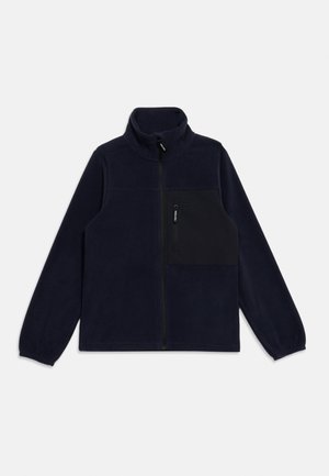 Veste polaire bleu marine avec fermeture éclair frontale complète et poche poitrine noire avec une petite fermeture éclair verticale.
