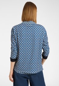 Blauw patroon lange mouwen shirt met geometrische ontwerpen, ronde halslijn en zwarte manchetten. Gemaakt van zachte stof met een ontspannen pasvorm.