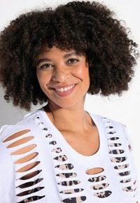 Valkoinen T-paita, jossa on suuret viilleet, jotka paljastavat alla olevan kuvioidun kankaan. Ominaisuuksiin kuuluu pyöreä kaula-aukko ja lyhyet hihat.