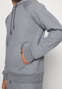 Felpa grigia con tasca a marsupio, polsini e orlo a coste. Realizzata in morbido misto cotone, con cappuccio con coulisse e maniche raglan.