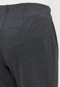 Dark gray trousers made from a textured fabric, featuring a smooth waistband and subtle stitching details along the side seams.