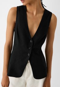 Svart lin väst med djup V-ringning, ärmlös design och tre framknappar. Har en skräddarsydd passform och slät yta.