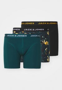 Drei Paare Herren-Boxershorts. Das vordere Paar ist einfarbig in Teal, das mittlere hat ein tropisches Muster und das hintere ist schwarz. Alle haben Markenbund.