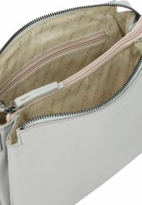 Borsa in pelle bianca con zip superiore aperta che mostra l'interno rivestito in tessuto beige e una tasca interna con zip.