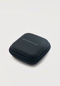 Συμπαγής μαύρη τετράγωνη θήκη με φερμουάρ και στρογγυλεμένες άκρες, με το λογότυπο Tommy Hilfiger και τη σημαία στην κορυφή, σε απλό λευκό φόντο.