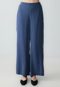 Pantaloni a gamba larga navy realizzati in tessuto leggero, con una texture liscia e una silhouette dritta, orlati in fondo.