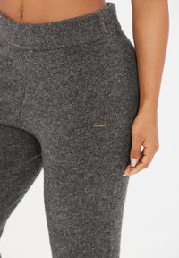 Gray knit leggings with a soft texture, a wide elastic waistband, and a small gold logo detail on the side.