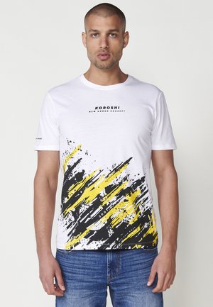 White cotton t-shirt featuring a black and yellow abstract brushstroke design with "KOROSHI" text in black on the chest area.