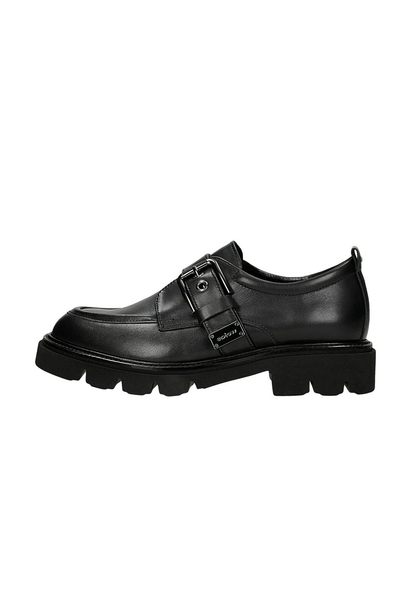 Zwarte leren loafer met een chunky zool, grote zilveren gesp en een trekband aan de hiel, getoond in zijaanzicht.