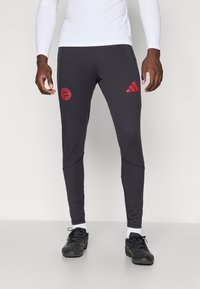 Sorte atletiske bukser med slim fit, med rødt Bayern München emblem på låret og tre striber logo på siden.