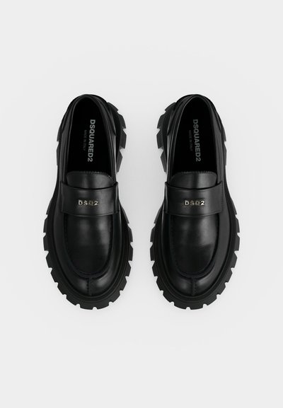 Une paire de mocassins en cuir noir avec des semelles crantées épaisses et le logo argenté DSQ2 sur la bride avant, vues de dessus sur fond blanc.