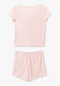 Set di pigiami rosa realizzato in tessuto a coste con motivi a cuori bianchi. Comprende una maglietta a maniche corte e pantaloni corti fino al ginocchio con orlo ondulato.