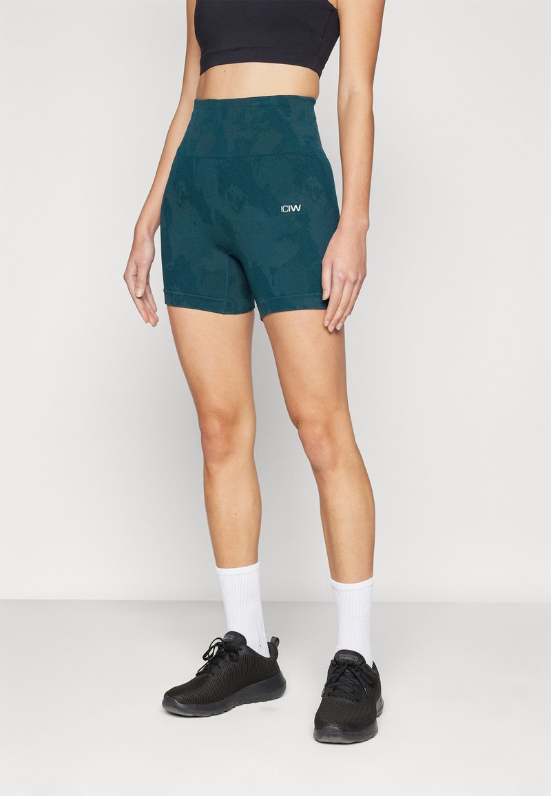 Teal høy midje sportsshorts med camouflasjemønster, laget av elastisk stoff. Inkluderer en liten hvit logo og flate sømmer for komfort.