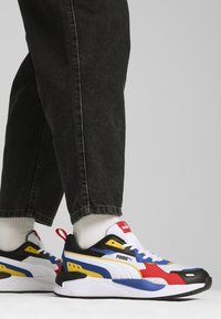 Baskets Puma présentant un mélange de noir, blanc, rouge, jaune et bleu. Tige en mesh texturé, col rembourré et semelle coussinée.