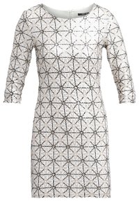 Witte jurk met zwart-beige geometrisch patroon, driekwart mouwen, ronde halslijn en rits aan de achterkant. Gestructureerd materiaal.