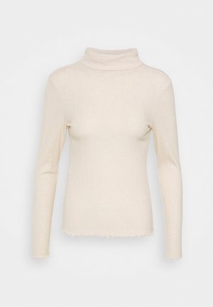 Haut à col roulé côtelé de couleur crème. Caractérisé par des manches longues, une coupe ajustée et des bords d'ourlet effilochés pour plus de texture. Tissu extensible.