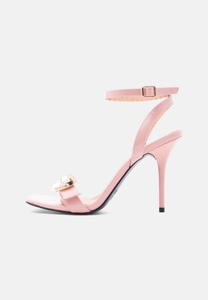 Pink patent leather stiletto sandal with ankle strap, open toe, and gold-tone metal ring detail on front strap.