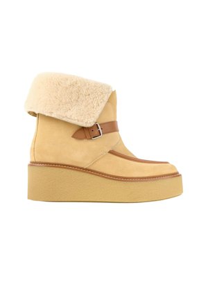 Botte plateforme beige en daim avec revers en fausse peau de mouton pliée et sangle en cuir marron avec boucle sur le côté, semelle épaisse.