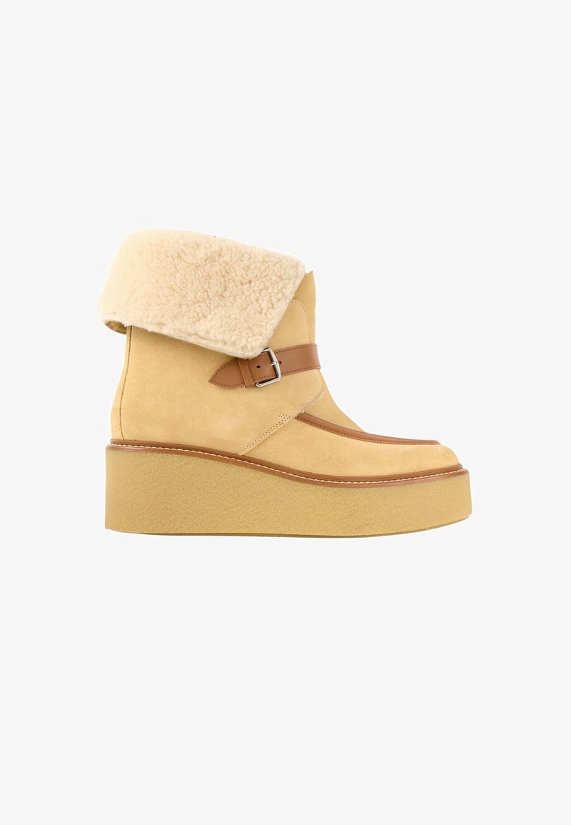 Botte plateforme beige en daim avec revers en fausse peau de mouton pliée et sangle en cuir marron avec boucle sur le côté, semelle épaisse.