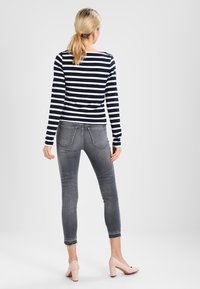 Granatowo-białe, w paski, długie rękawy bluzka w połączeniu z szarymi, wąskimi dżinsami i jasnoróżowymi szpilkami. Dżinsy mają wyblakły kolor z lekko postrzępionymi końcami.