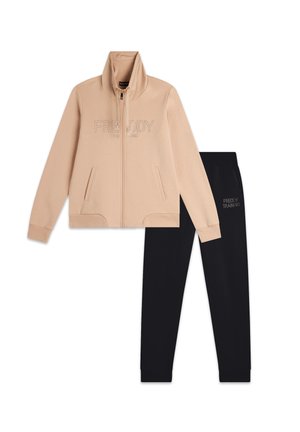 Veste zippée beige avec col haut et détail de logo, associée à un pantalon de survêtement noir arborant un logo assorti. Les deux articles sont en mélange de coton.