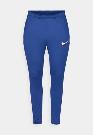Blauwe sportbroek met een elastische tailleband. Heeft een klein oranje Nike-logo aan de onderzijde aan de linkerkant. Soepele, rekbare stof.