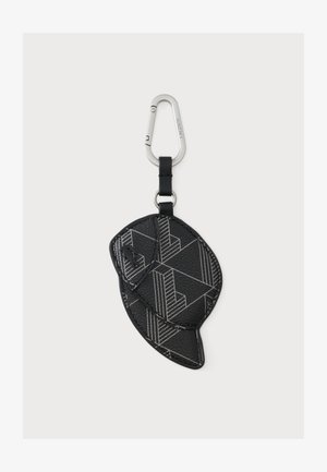 Porte-clés en cuir noir en forme de casquette avec des motifs géométriques, attaché à un mousqueton argenté étiqueté Lacoste.