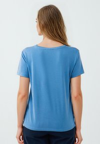 Niebieska koszulka z krótkim rękawem i okrągłym dekoltem, wykonana z miękkiego materiału. Gładka tekstura z lekkim krojem, charakteryzująca się regularnym fasonem.