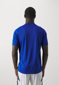 Kongelig blå, kortermet sportstrøye med rund hals og glatt tekstur, vist fra baksiden. Ingen synlige logoer eller mønstre.