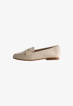 Beige instappers met een gestructureerd stoffen bovenwerk, platte bruine zool en een decoratieve band aan de voorkant. Klassiek instapontwerp.