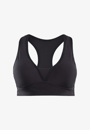 Kryté legíny v multicolor s geometrickými vzory v jasných odstínech na černém podkladu, spárované s černým sportovním topem a bílými teniskami.