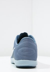 Blue athletic shoe with a textured mesh upper, round toe, padded collar, and a flexible rubber sole. Features a white logo accent.