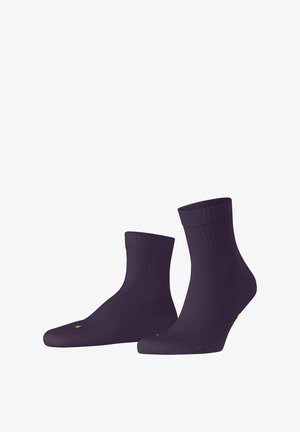 Chaussettes de cheville violettes avec des bords côtelés, fabriquées à partir d'un matériau extensible. Présente une couture de orteil sans couture et un détail de logo jaune sur le côté.