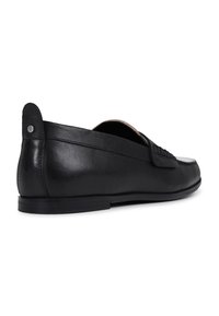 Mocasines de cuero negro con un acabado suave, forma redondeada, diseño de perfil bajo y un pequeño acento decorativo cerca del talón.