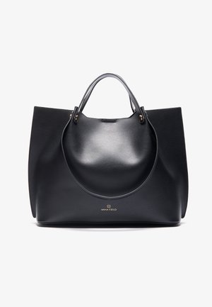 Bolsa tote de couro preto com textura suave, duas alças superiores e um detalhe central arredondado. Apresenta um logótipo dourado na base.
