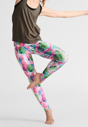 Leggings multicolores con un patrón floral que presenta tonos de rosa, verde y azul. Una blusa de tirantes oscura y ligera complementa el conjunto.
